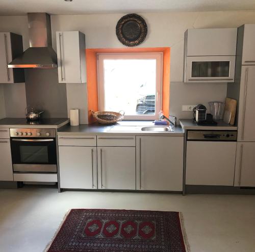 eine Küche mit weißen Schränken, einem Waschbecken und einem Fenster in der Unterkunft Exklusive Ferienwohnung in Außervillgraten