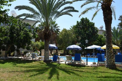 a group of chairs and umbrellas next to a pool at Odysseas & Eleni Hotel Apartments in Polis Chrysochous