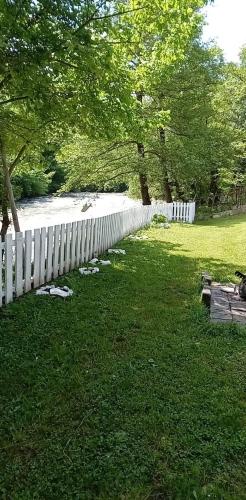 a white fence in the grass next to a river at Apartman Amina-Ahmad Vinac-Jajce in Jajce