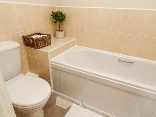 a bathroom with a toilet and a white bath tub and a toilet at The Milne in Todmorden