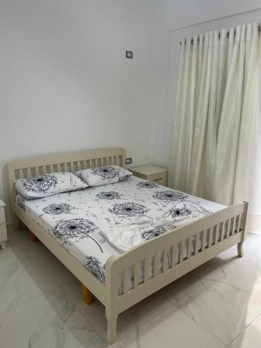 um quarto com uma cama com um edredão branco e preto em Taku apartment em Saranda