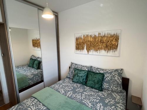 a small bedroom with a bed and a mirror at Rona Apartments in Novi Sad