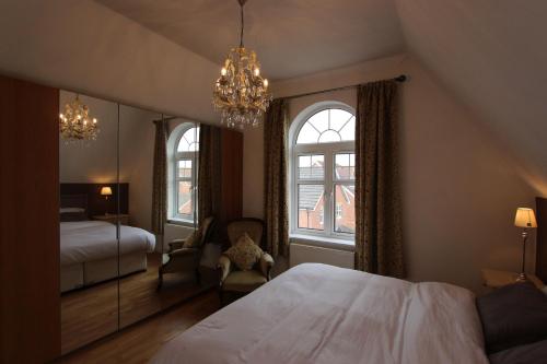 a bedroom with a bed and a chandelier and two windows at Immaculate 4BD Family Home in Lee on the Solent in Lee-on-the-Solent