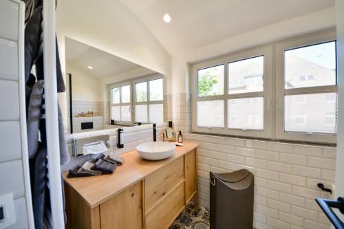 ein Badezimmer mit einem Waschbecken und zwei Fenstern in der Unterkunft Ferienhaus Olivenoog in Wangerooge