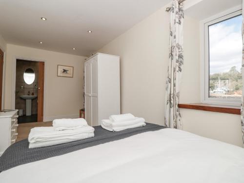 1 dormitorio con 1 cama con sábanas blancas y ventana en Spanish Boathouse en Brixham