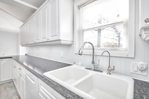 a white kitchen with a sink and a window at Muskoka Getaway-Trails/Hot Tub/Hike/Fish/Ski/Relax in Honey Harbor