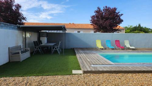 Sainte-SoulleにあるStudio 3 personnes avec piscineの裏庭(スイミングプール、椅子、テーブル付)
