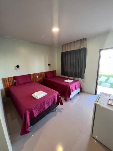 a room with two beds and a window at Pousada Mangaba in Barreirinhas