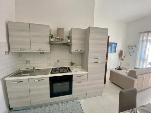 a kitchen with white cabinets and a stove top oven at Monolocale Nonna Ita in Santa Teresa Gallura