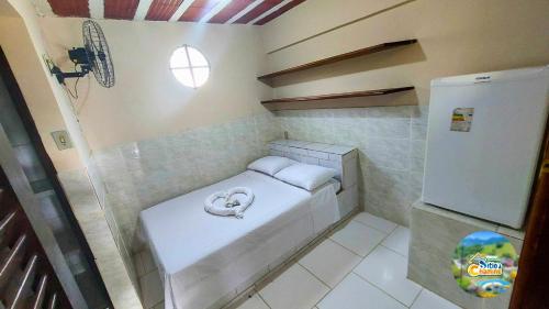 Piccola camera con letto piccolo e frigorifero. di Hospedaria e Alojamento SítioChaminé Piscinas Naturais a Itaguaí