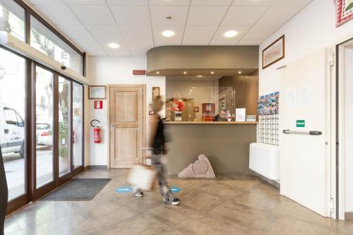 a person walking down a hallway in a store at Hotel Domomea in Alghero