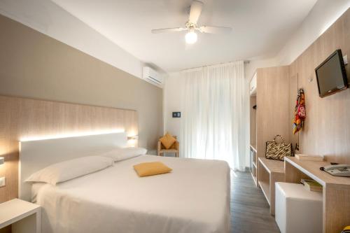 um quarto com uma cama branca e uma ventoinha de tecto em Hotel Etna em Caorle