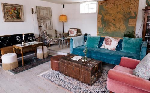 ein Wohnzimmer mit einem blauen Sofa und Stühlen in der Unterkunft Sköllengården in Simrishamn