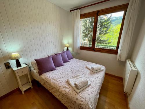 a bedroom with a bed with purple pillows and a window at C20 - Alojamiento en Edif. Pirineos Cerler - Villmor in Cerler