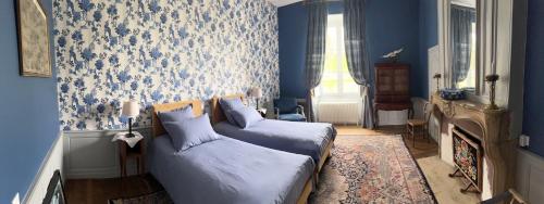 a bedroom with blue walls and a bed and a fireplace at Château de Mauvilly in Mauvilly