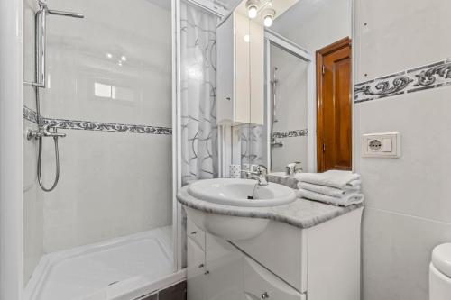 La salle de bains blanche est pourvue d'un lavabo et d'une douche. dans l'établissement Casa Mon, à Costa Teguise