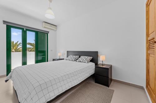 a white bedroom with a bed and a window at Casa Mon in Costa Teguise