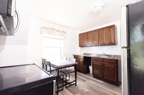 a kitchen with wooden cabinets and a table with chairs at Hillside Motel in Saint John