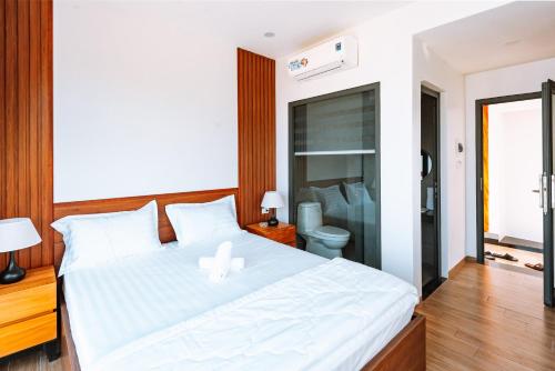 a bedroom with a white bed and a bathroom at Ngọc Hoa - Nam Hội An Hotel in Thăng Bình