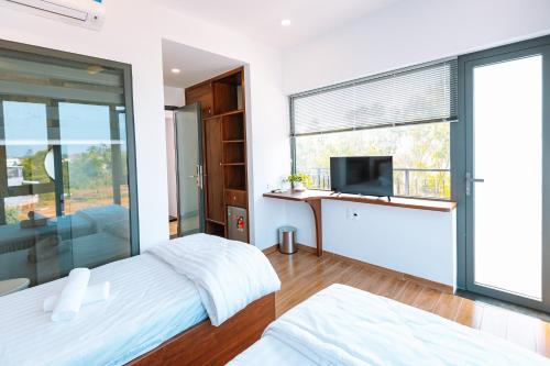 a bedroom with a large window and a tv at Ngọc Hoa - Nam Hội An Hotel in Thăng Bình