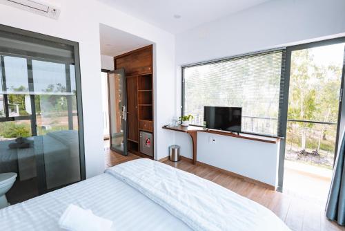 um quarto com uma cama, uma televisão e uma janela em Ngọc Hoa - Nam Hội An Hotel em Thăng Bình