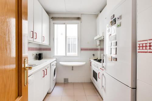 een keuken met witte kasten, een wastafel en een raam bij Luxury apartment around Serrano and Juan Bravo in Madrid