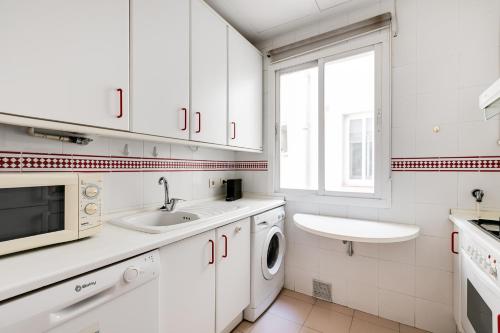 een witte keuken met een wastafel en een wasmachine bij Luxury apartment around Serrano and Juan Bravo in Madrid