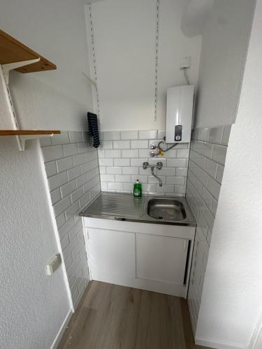 eine kleine Küche mit einem Waschbecken und weißen Fliesen in der Unterkunft Apartment City und Stadionnah I Privatparkplatz inklusive I in Dortmund