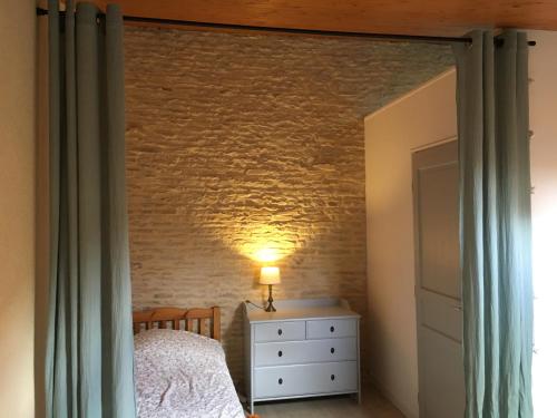 1 dormitorio con cama y pared de ladrillo en Gîte de la cour, en Arçais