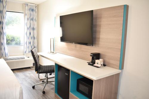 a room with a desk with a tv on a wall at Clarion Pointe Vidalia - Lyons West in Vidalia