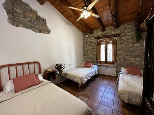 a bedroom with two beds and a stone wall at Cal Caminer Casa rural con piscina y barbacoa in Guimerá