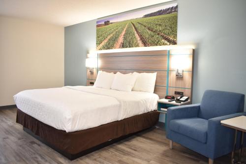 a hotel room with a bed and a blue chair at Clarion Pointe Vidalia - Lyons West in Vidalia