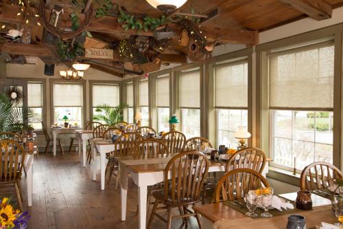 a dining room with tables and chairs and windows at 1825 Inn Bed and Breakfast in Palmyra