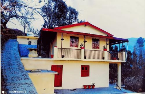 ナイニタールにあるWelcome homestayの赤いドアとバルコニー付きの小さな家