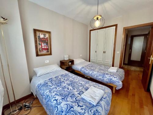 Habitación con 2 camas y lámpara. en Agradable Apartamento en el Centro de Burgos Parking Free ATUAIRE, en Burgos