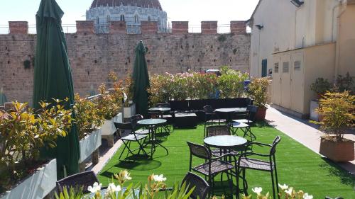 a patio with tables and chairs in front of a wall at Hotel Il Giardino in Pisa
