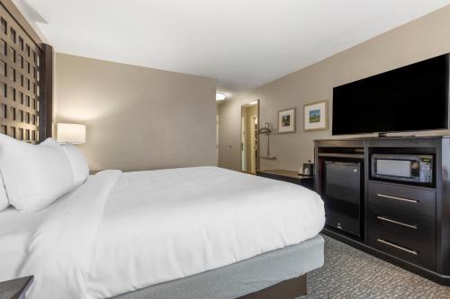 a hotel room with a bed and a flat screen tv at Comfort Inn Plano-Dallas in Plano