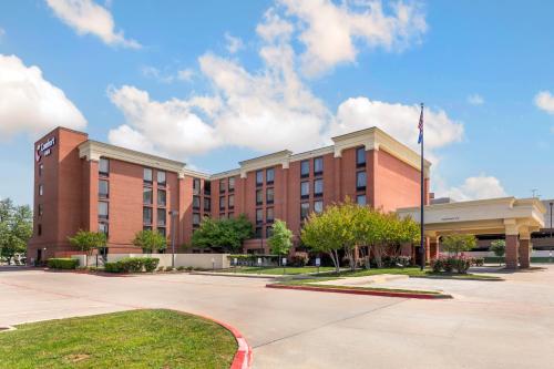 a large red brick building with a flag at Comfort Inn Plano-Dallas in Plano