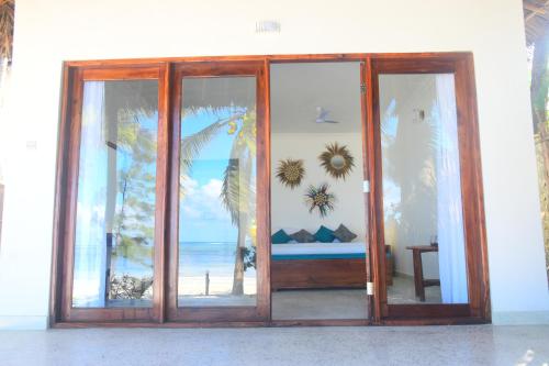 een glazen schuifdeur met uitzicht op het strand bij Blue Palm Zanzibar in Bwejuu