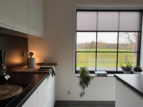 eine Küche mit weißen Schränken und einem großen Fenster in der Unterkunft De Bovenbuur in Lummen