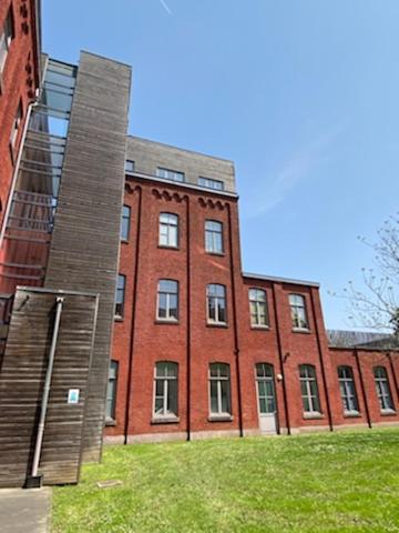 a large red brick building in front of a building at Roubaix près Lille, un cocon en plein centre in Roubaix