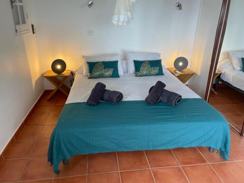 una camera da letto con un grande letto con lenzuola e cuscini blu di Villa Libellule a Grand-Bourg