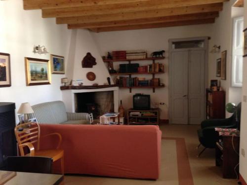 a living room with a red couch and a fireplace at Traditional house Zia Dina in Mògoro
