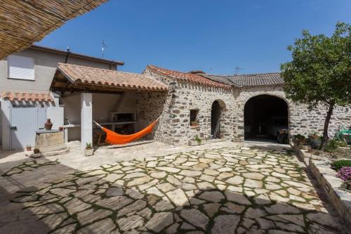 a stone house with an orange hammock in the courtyard at Traditional house Zia Dina in Mògoro