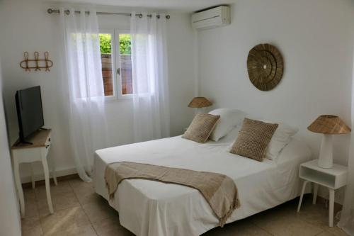 een witte slaapkamer met een bed en een televisie bij Maison idéale à 3min de la plage in Mandelieu-la-Napoule