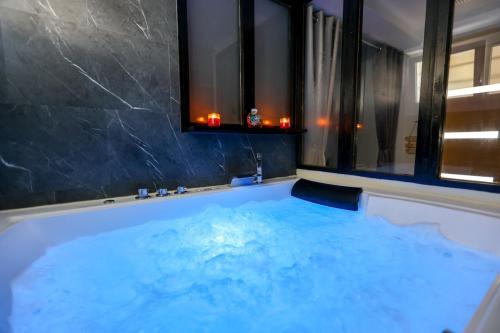 a large tub with blue water in a bathroom at Appart' Cocooning & Double Balneotherapy - Cognac Center in Cognac