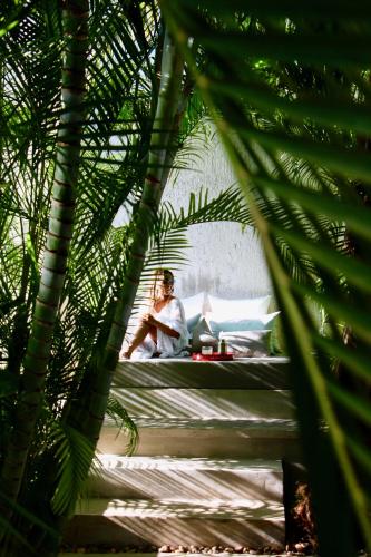 a person sitting on a bed in a room with palm trees at The Diplomat Boutique Hotel in Mérida
