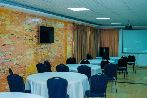 a conference room with tables and chairs and a screen at Midindi Hotel in Accra