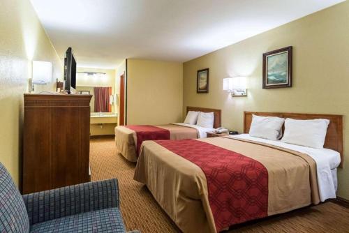 una habitación de hotel con 2 camas y una silla en The Residency Inn, en Galveston