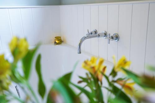 a bathroom sink with a faucet and some flowers at Aldeburgh Cottage in Aldeburgh